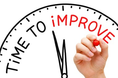 Hand writing Time to Improve concept with red marker on transparent wipe board.